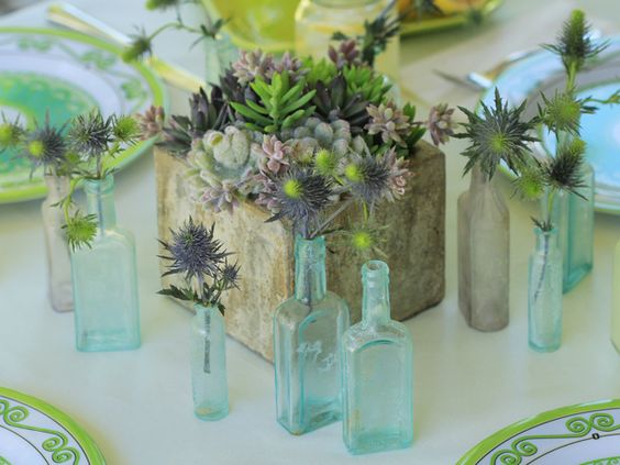 Square Concrete Block Centerpiece with Succulents Surrounded by Small Bud Vases – shared by HGTV